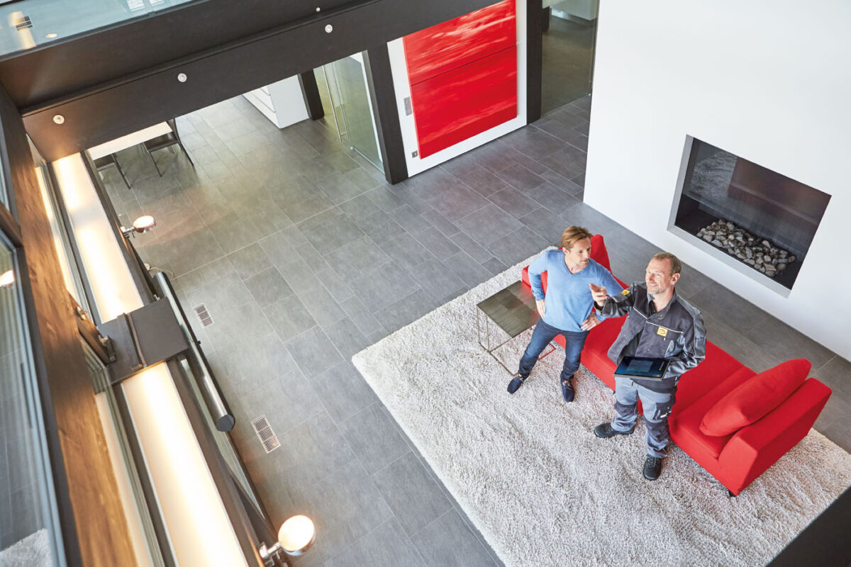 Elektrofachmann zeigt dem Kunde im Wohnzimmer die Beleuchtung (2)